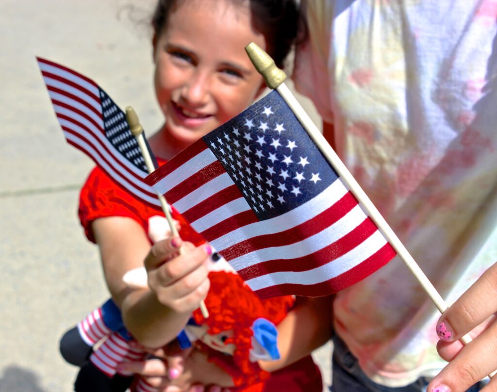 Military child at Veterans Day Parade with American Flag