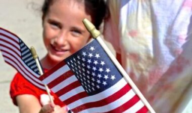 Military child at Veterans Day Parade with American Flag