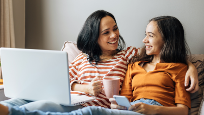 mother and daughter smiling behind a laptop